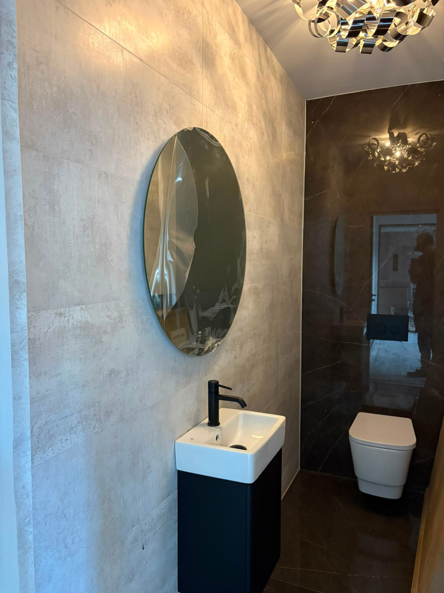 Downstairs cloakroom with wall hung basin unit, concealed cistern and round mirror